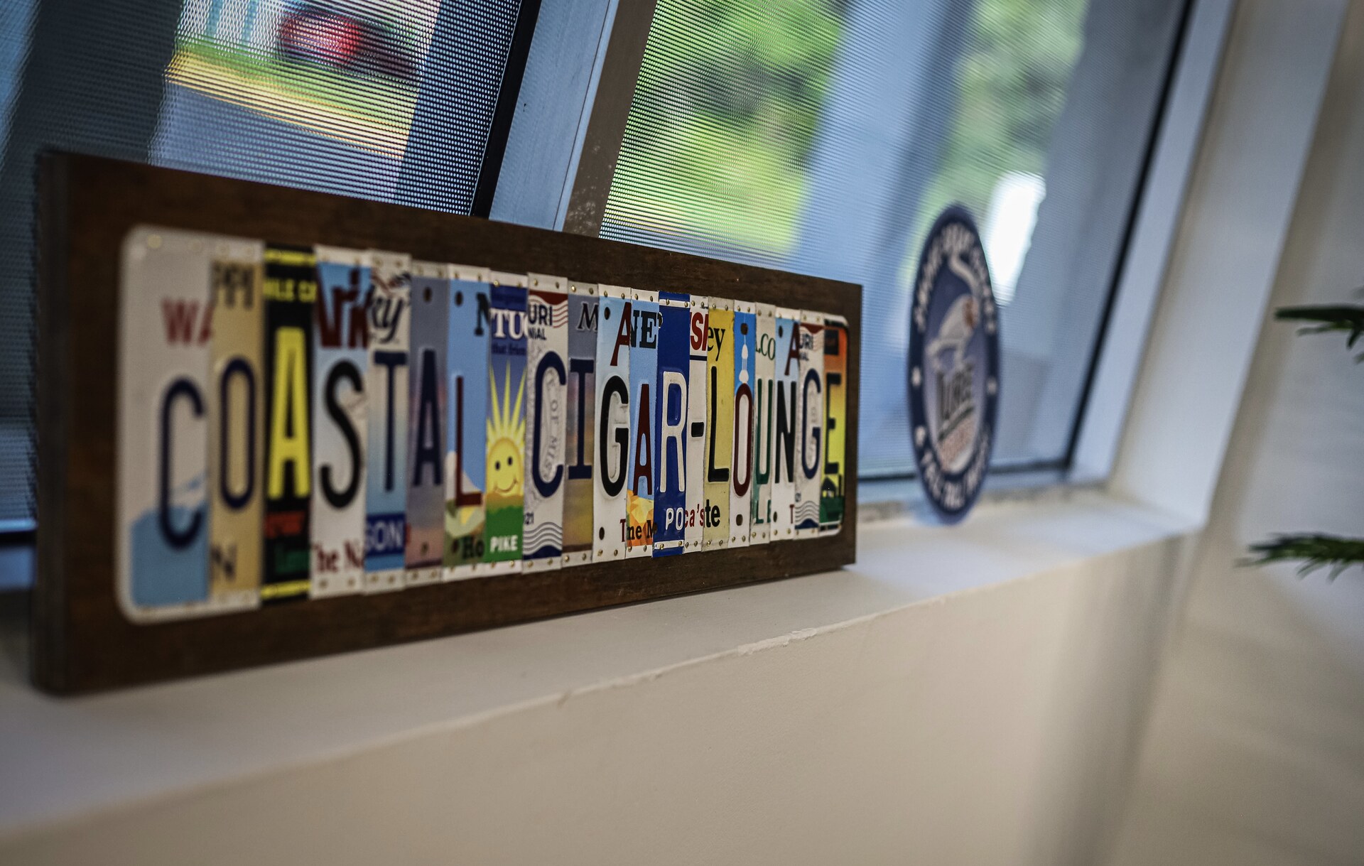 Coastal Cigar Lounge license-plate artwork on a windowsill